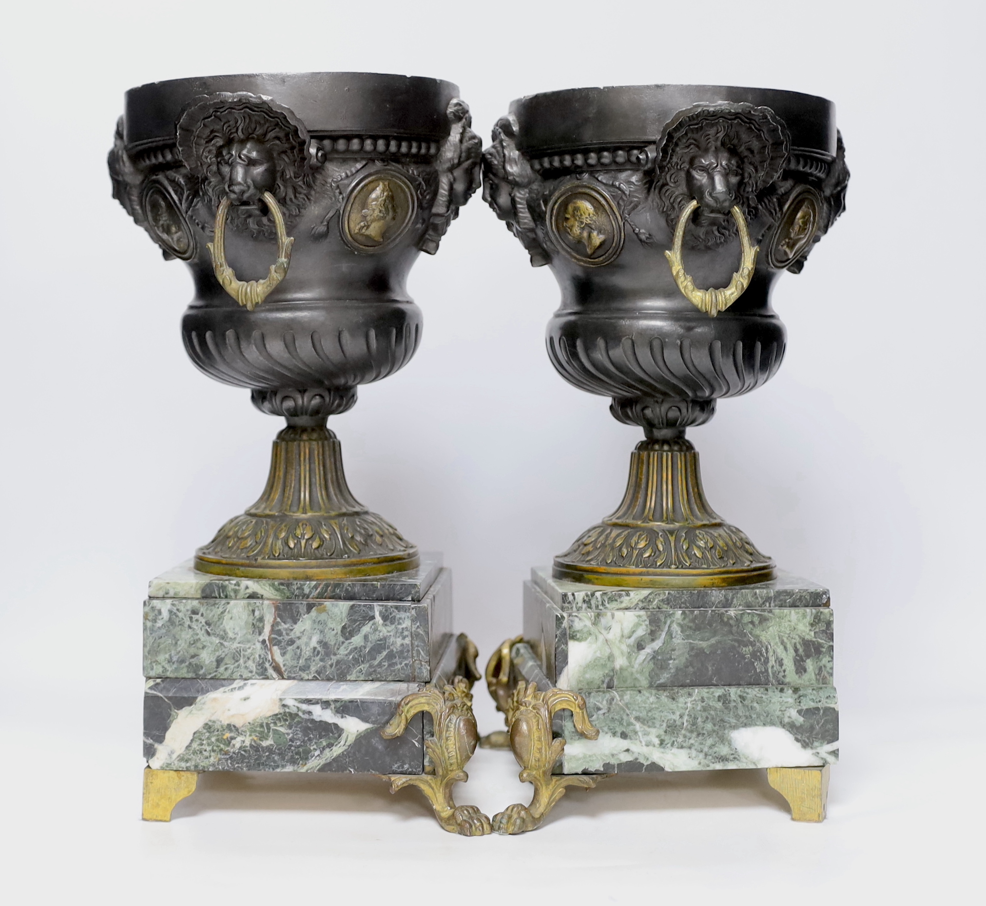 A pair of late 19th century French gilt metal and brown patinated urns, decorated with masks and serpentine plinths, 33cm high